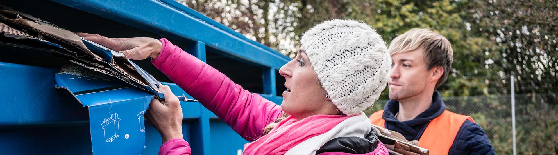 Photo de deux personnes qui jettent leurs cartons usager dans le conteneur prévu à cet effet en déchèterie