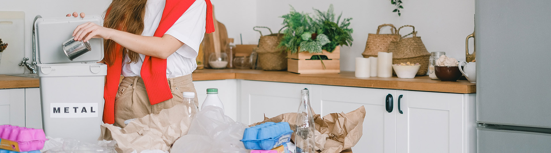 Photo de différents déchets posés sur un table avec une personne qui dépose les déchets métalliques dans une poubelle où il est indiqué "métal"