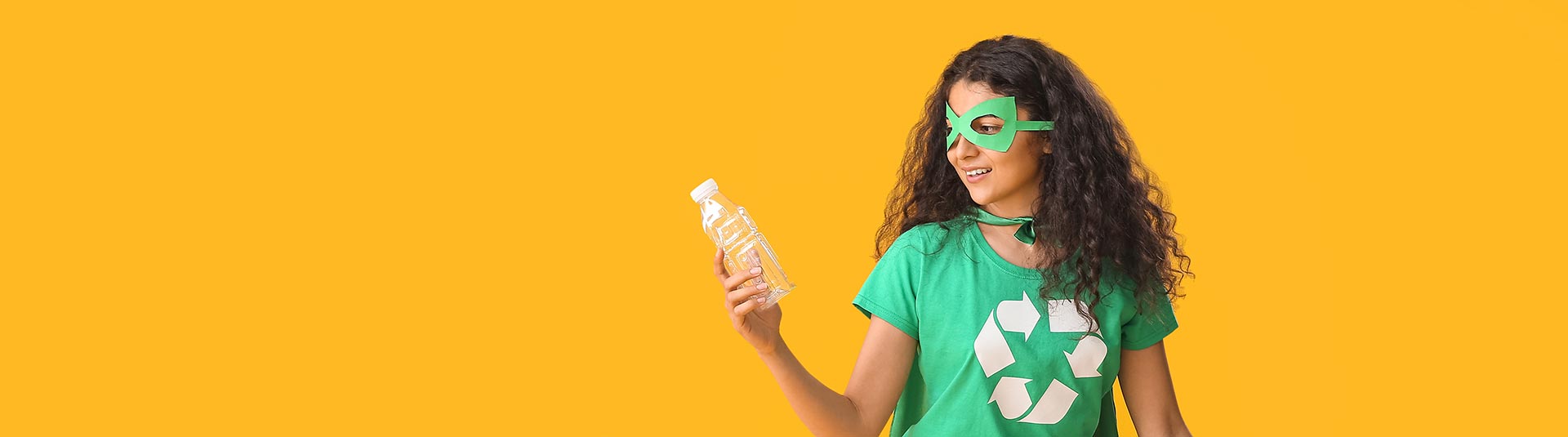 Photo d'une fille déguisée en super héro avec un teeshirt avec le pictogramme du recyclage et une bouteille en plastique à la main
