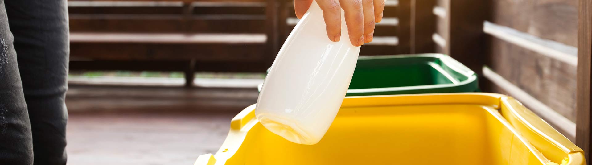 Photo d'une main qui dépose une bouteille en plastique dans un bas de tri jaune