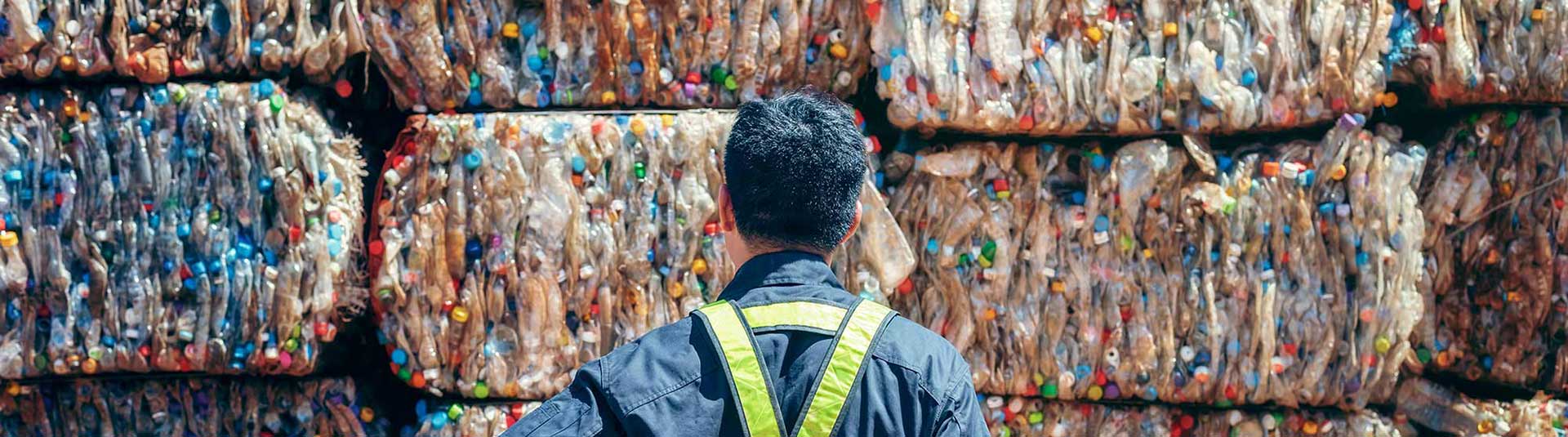 Photo d'un agent devant des balles de déchets compactés